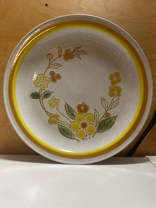 Sunny speckled floral serving plate featuring a ceramic design with a yellow floral motif, gold and orange rim, and painted leaves from International China’s Country Meadow line.