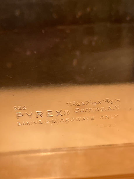 Underside of a PYREX Corning Vision Ware amber baking dish, showing embossed markings and dimensions, indicating suitability for baking and microwave use.