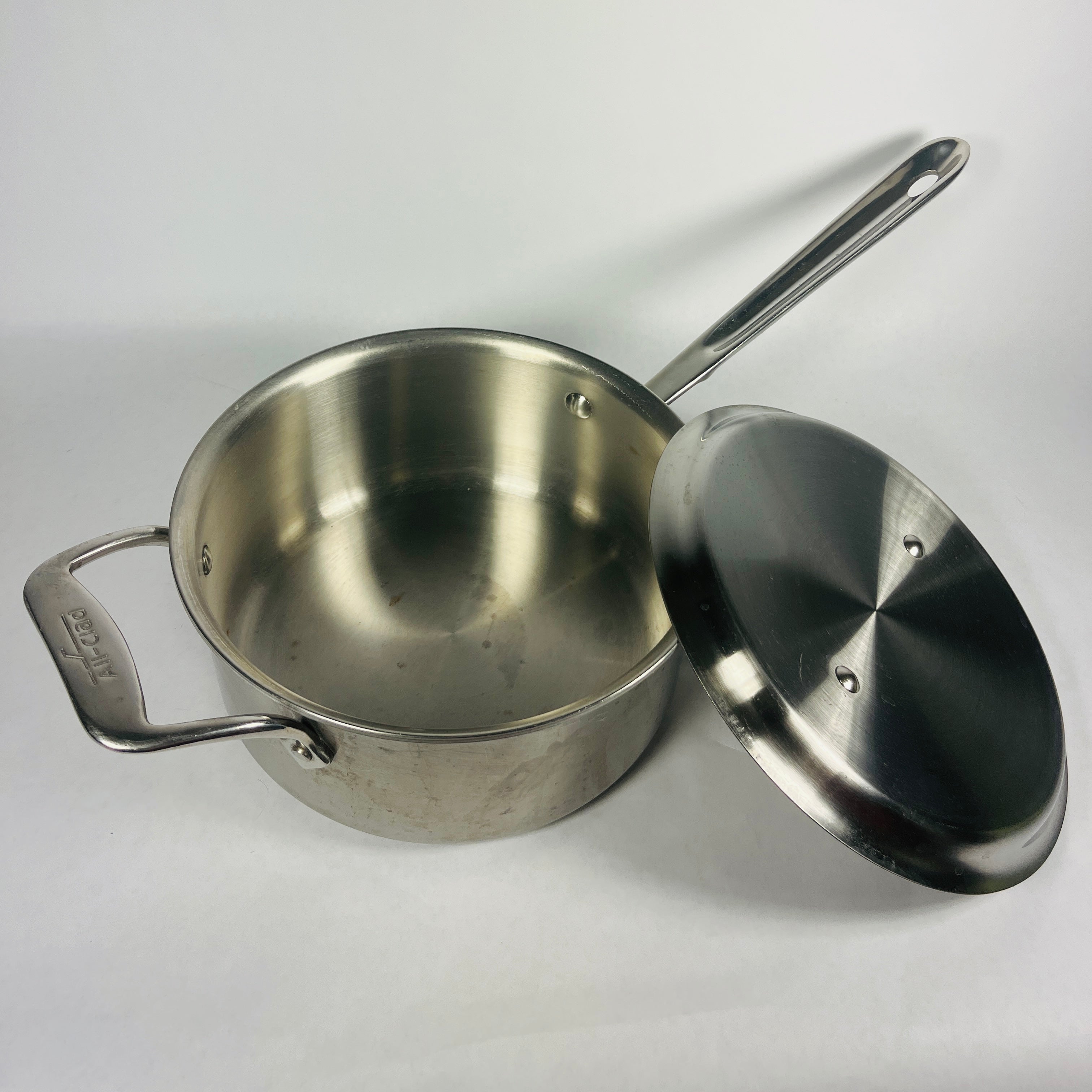 https://spoonskitchenexchange.com/cdn/shop/files/All-Clad-saucepan-with-lid-open-spoons-kitchen-exchange.jpg?v=1686086294