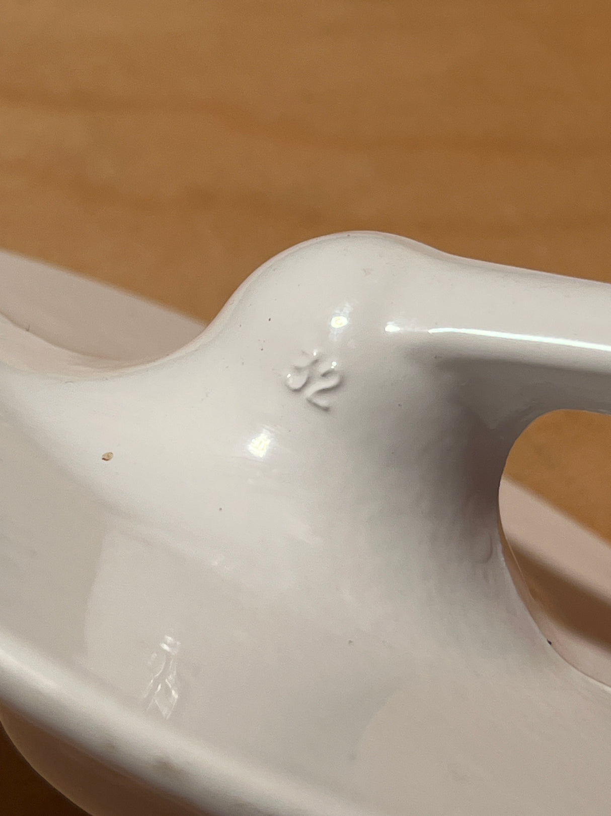 Dough hook attachment for Kitchenaid stand mixer, shown as a white glazed ceramic spoon rest with a central hump stamped “32” for utensil placement.