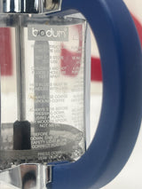 Bodum single serve French press coffee maker with navy handles, shown close-up, highlighting its compact design for easy, single-serving coffee preparation.