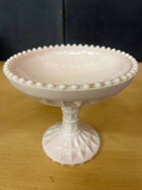 Jeanette pale pink milk glass pedestal candy dish with geometric crisscross pattern and raised bumps, showcasing vintage charm and a seamless pedestal design.