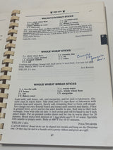 Spiral-bound cookbook An Apple a Day open to Breads section, featuring three bread-stick recipes and a tip for creative presentations.