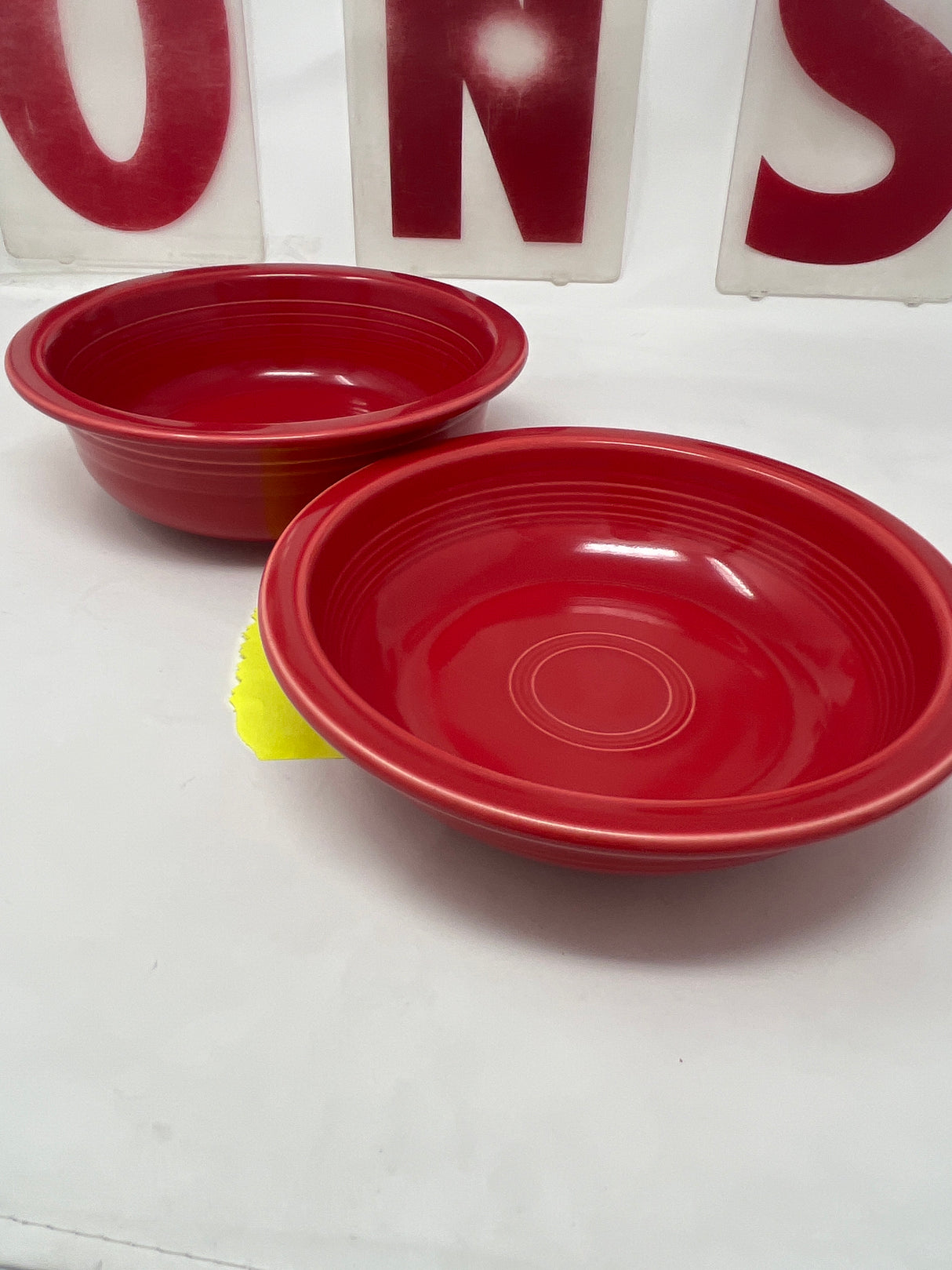 Fiestaware by Homer Laughlin scarlet red ceramic bowls, featuring one large deep bowl and one smaller vintage-style bowl on a white surface.