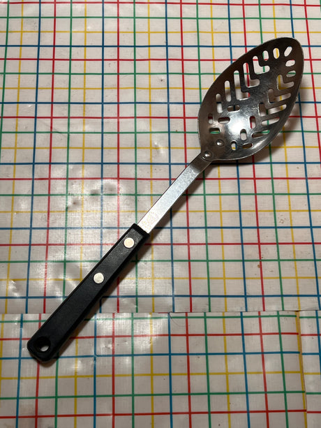 Slotted serving spoon - stainless steel with Bakelite handle - EKCO Forge, featuring a perforated bowl for efficient draining, displayed on a patterned surface.