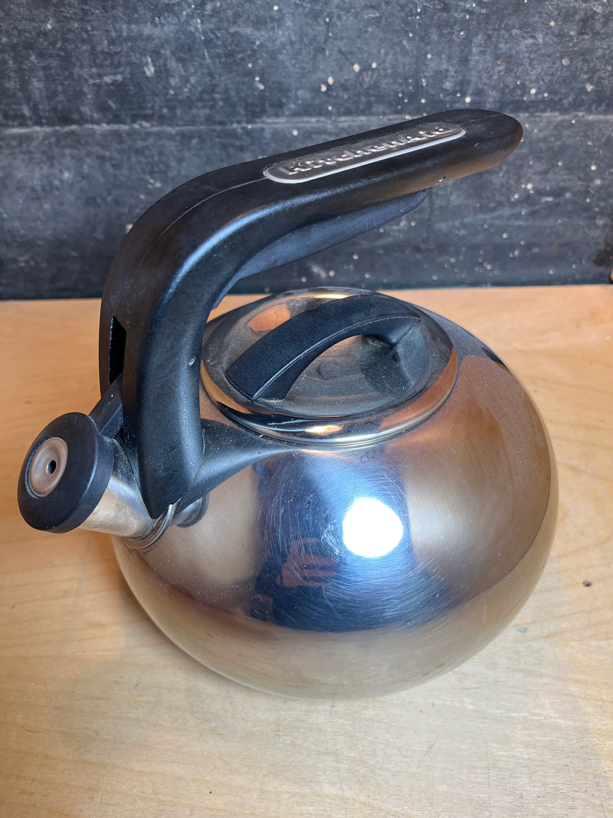 Whistling tea kettle - Kitchenaid 2 quart / 1.9L stainless steel with black handle, featuring a domed lid and arched handle, sits on a wooden surface.