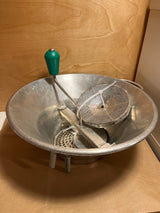 Louis Teller 3.5qt rotary food mill potato ricer featuring a metal bowl, green-handled crank, and interchangeable perforated discs, secured with a plastic cable tie.