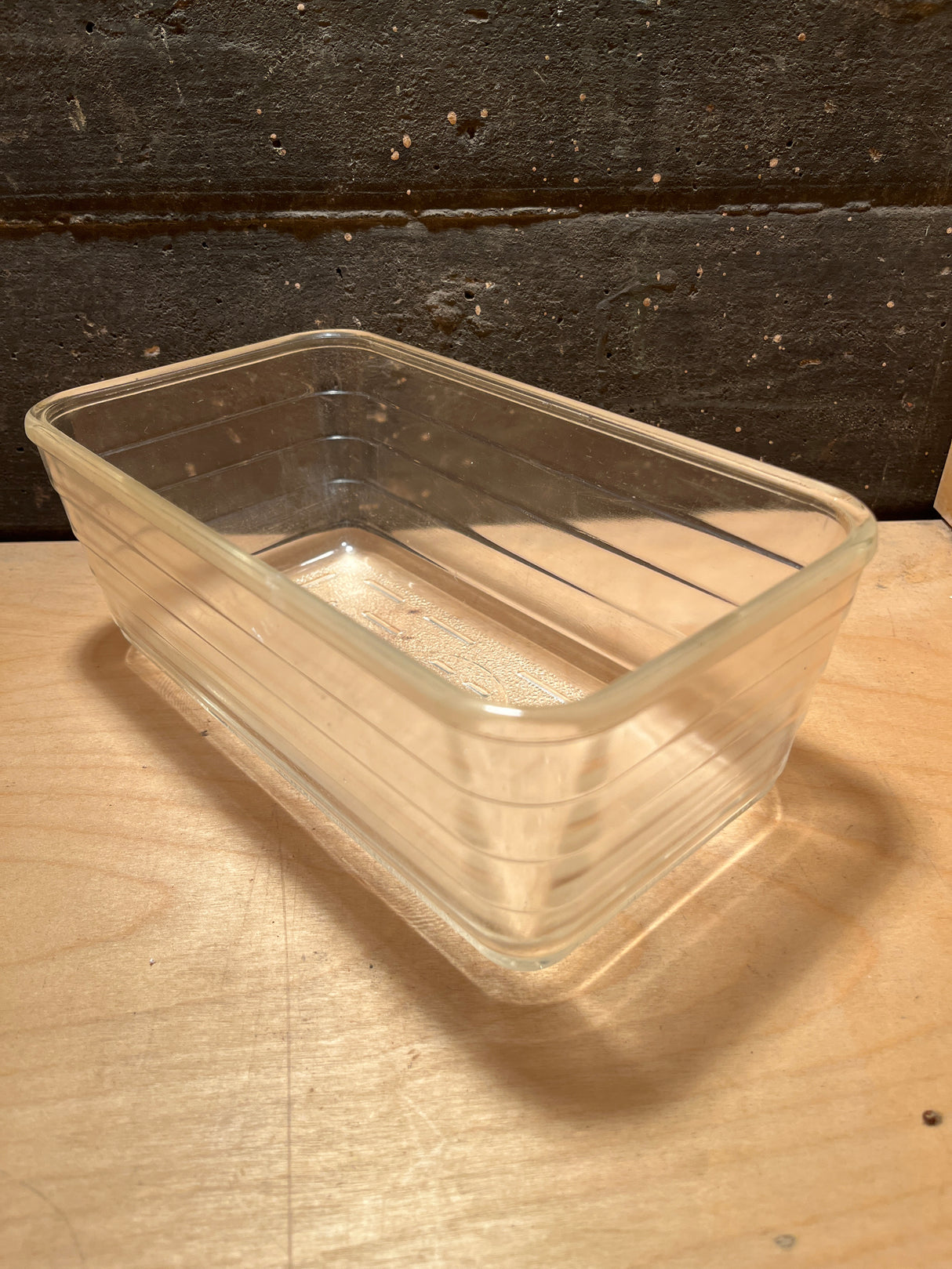 Glass ribbed loaf baking pan - vintage Glasbake - style #59, transparent rectangular dish with rounded corners and subtle ridges, displayed on a wooden surface.