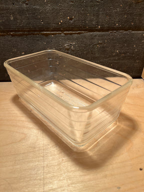 Glass ribbed loaf baking pan - vintage Glasbake - style #59, transparent rectangular dish with rounded corners and subtle ridges, displayed on a wooden surface.