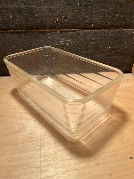Glass ribbed loaf baking pan - vintage Glasbake - style #59, transparent rectangular dish with rounded corners and subtle ridges, displayed on a wooden surface.