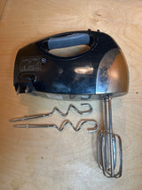 Hand mixer - Oster 6-speed 2577 with retractable power cord, shown with wire beaters attached and spiral dough-hooks beside it on a wooden surface.