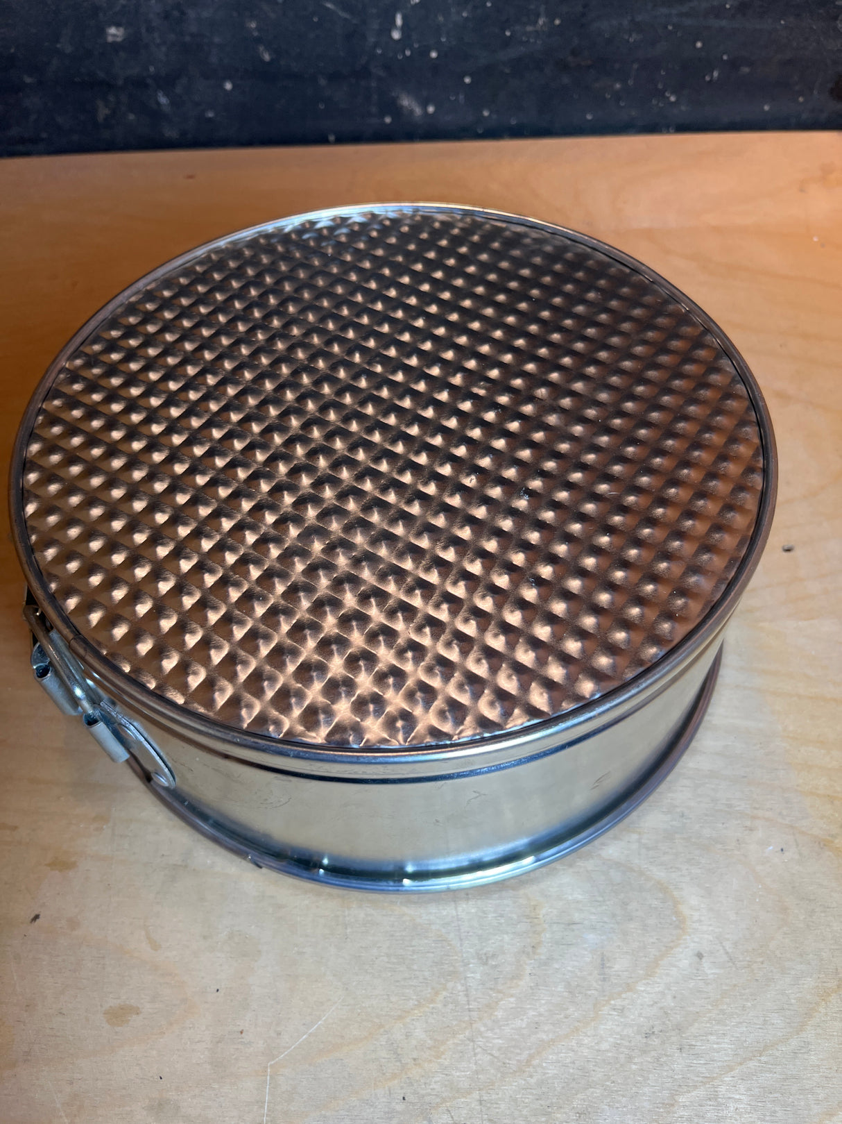 Springform cake pan - light tin 8” diameter, shown upside-down with textured base visible and side clasp for easy removal, perfect for baking delicate dishes.