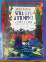 Still Life with Menu cookbook by Mollie Katzen, featuring a cover with a table, fruit, and flowers, emphasizing accessible, genuine cooking amidst busy lifestyles.