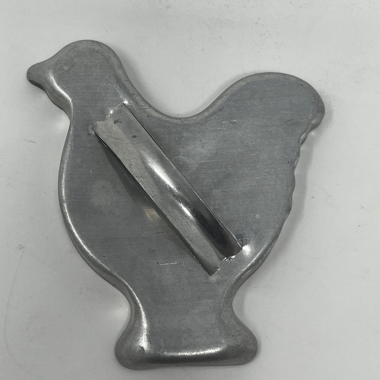 Mid century metal cookie cutters in various shapes like birds and chickens, on a metal surface.