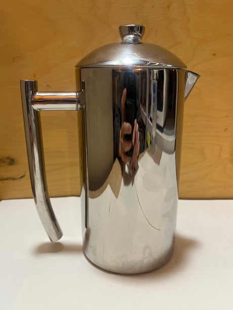 Frieling stainless steel French press coffee maker with a handle, spout, and domed lid, resembling a teapot, on a white surface.