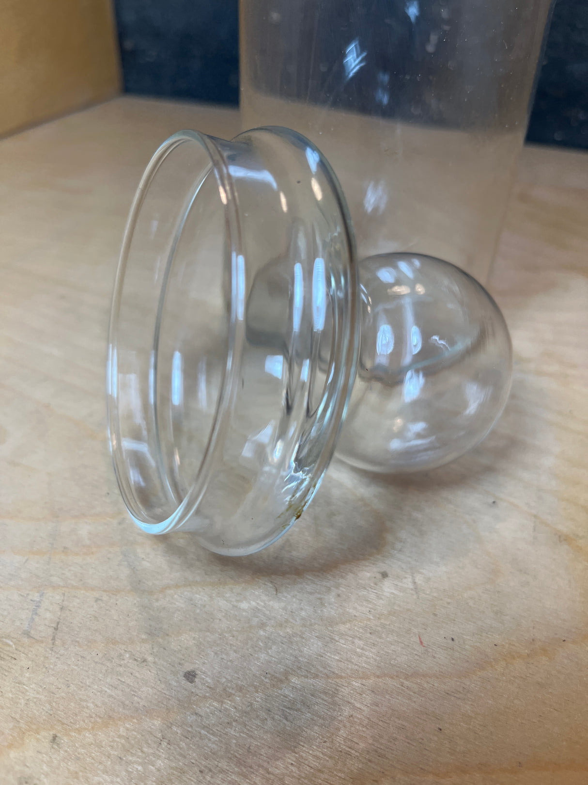 Libbey tall apothecary jars, featuring clear glass spherical-bottom vessels with flared rims, lie on a wood surface, resembling therapeutic cupping tools or mini terrarium containers.