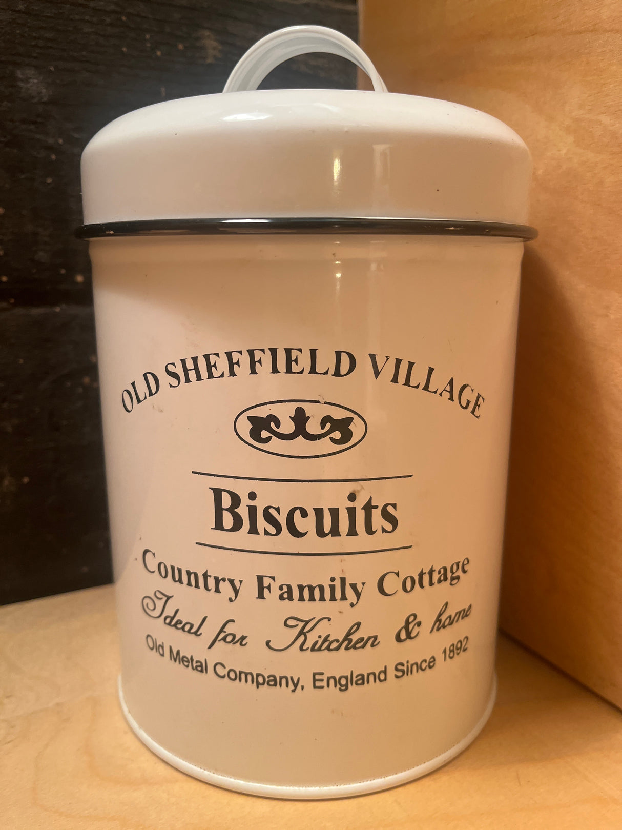 Old Sheffield Village Country Family Cottage Biscuits tin, a vintage-style white metal container ideal for storing treats, adding charm to any kitchen.