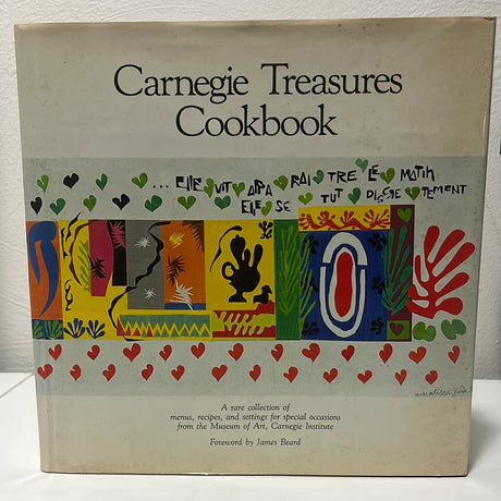 Carnegie Treasures Cookbook on a table, showcasing culinary art inspired by museum masterpieces, with close-up details of accompanying images and text.