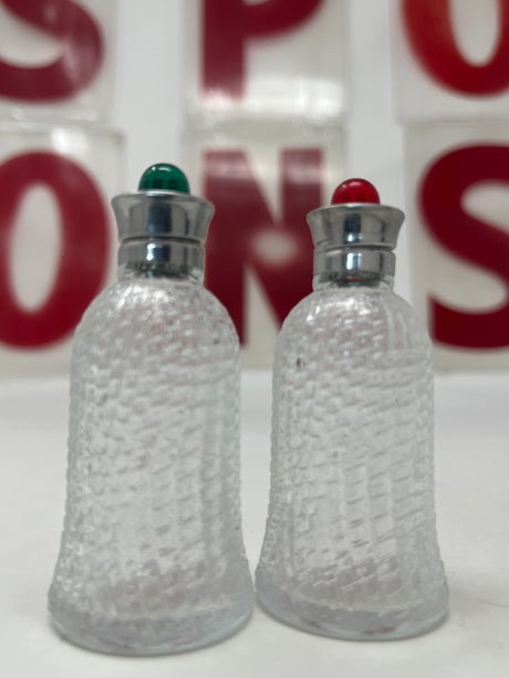 1950s red and green glass salt and pepper shaker set with textured glass, featuring metal hardware, displayed indoors on a table.