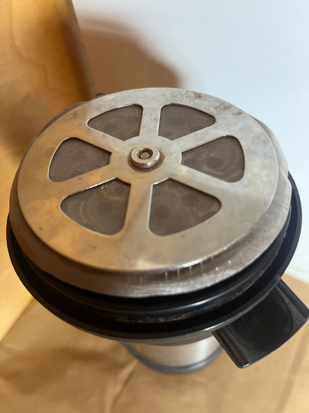 Top view of the Thermos Nissan stainless steel insulated French press coffee maker's plunger and mesh filter assembly, featuring a metal cross-plate and fine screen.