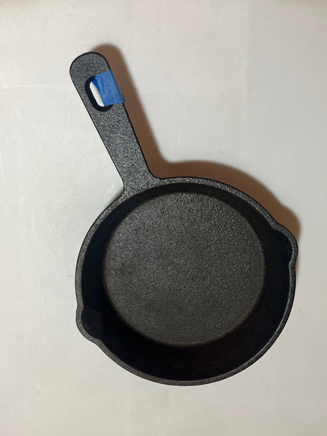 Crofton 6” teeny cast iron frying pan with deep sides, dual pouring spouts, and hanging hole with blue tape, ideal for baking dips or frying spices.