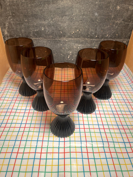 Set of 5 brown glass water goblets - vintage Lenox Nutmeg line with sturdy ridged bases and smooth bowls, displayed on a patterned tablecloth.
