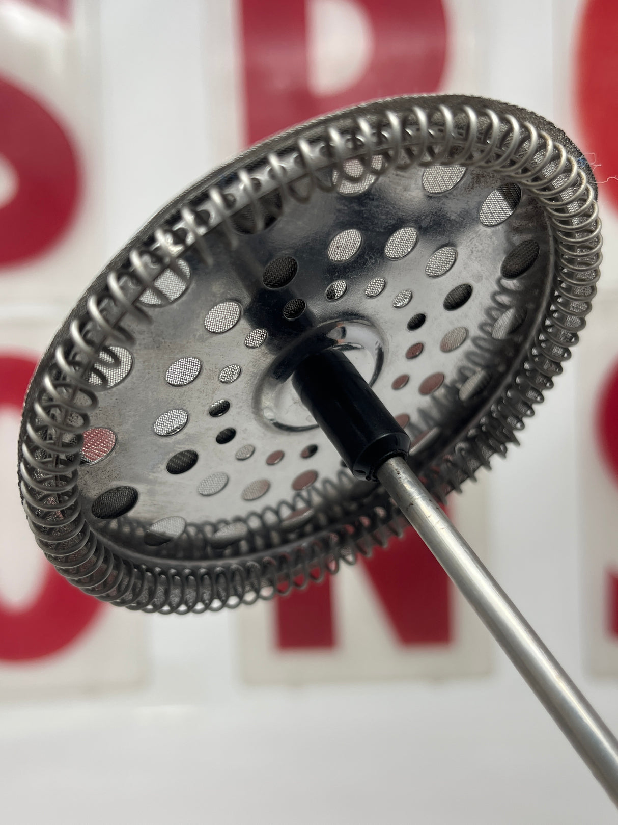 Close-up of Bodum Kenya single-serve French press coffee maker, showcasing its metal mesh design and round, textured components for brewing rich, flavorful coffee.