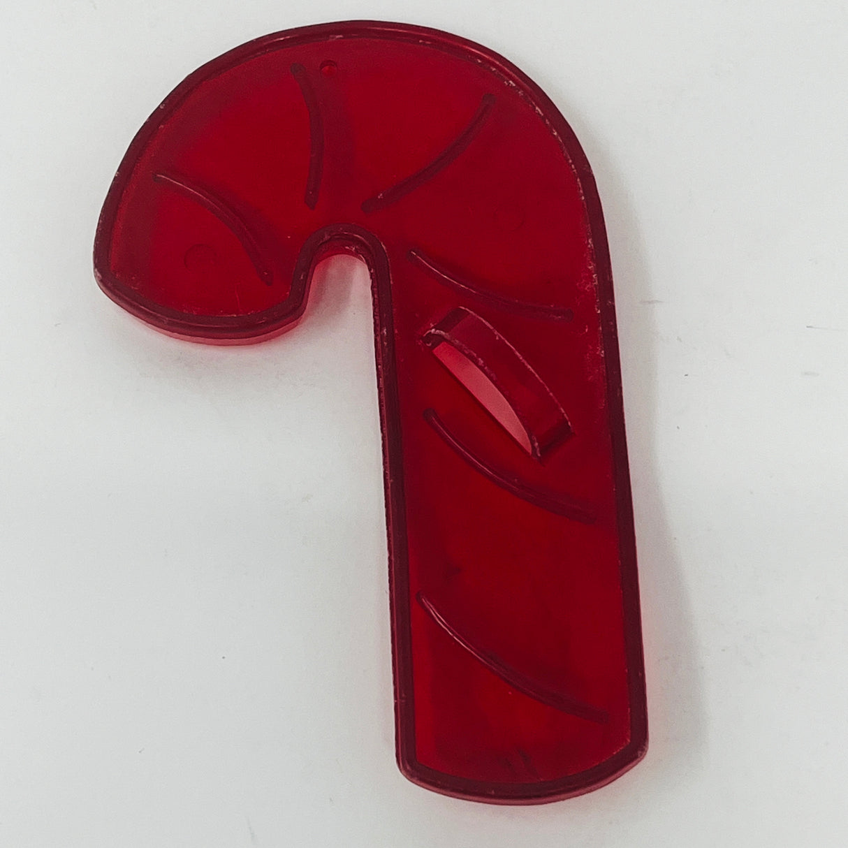 Red plastic mid century cookie cutters in various shapes including a candy cane and a fish on a surface with a circle.