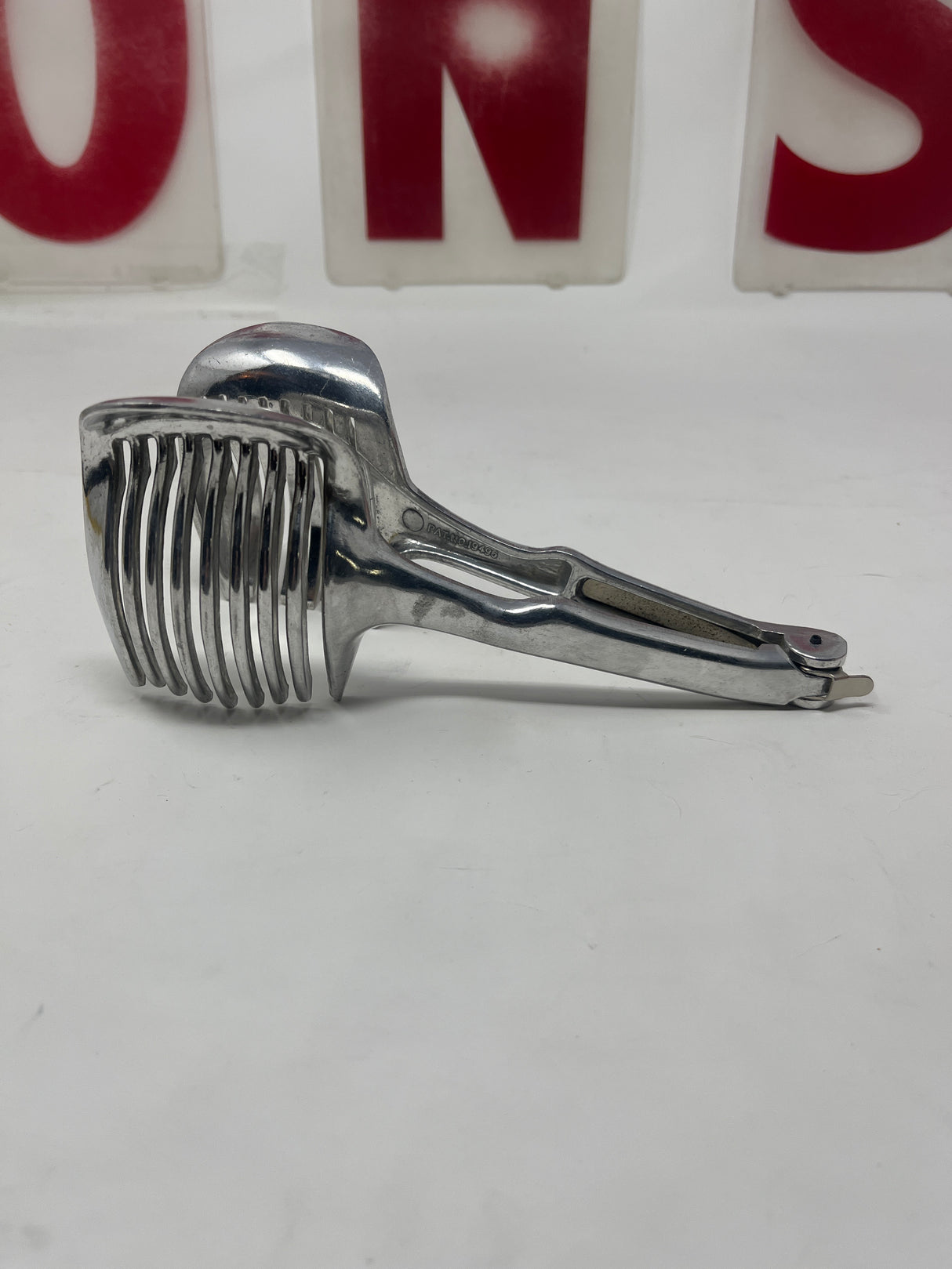 Vintage tomato slicer multipurpose tool with a metal handle and forked end, ideal for precise slicing. Close-up shows sturdy construction and screw detail.