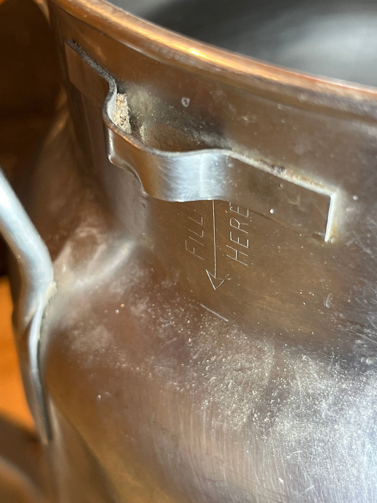 Close-up of Vintage John Wood Young’s Dairy stainless steel milk can interior, showing basket-support clip and embossed “FILL HERE” arrow marking the water fill line.