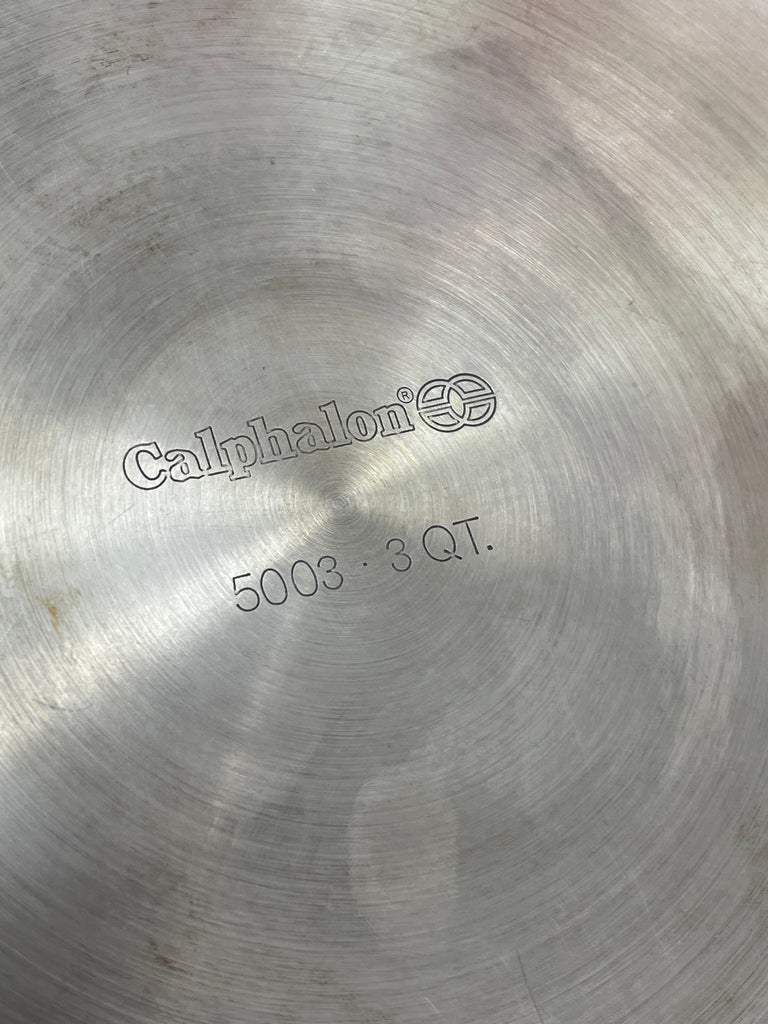 Close-up of Calphalon 5003 3qt sauté pan's metal surface, highlighting the brand logo and numerical details.