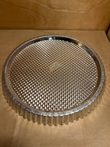 Pampered Chef stainless steel flan pan, round with fluted edges and removable, textured bottom, ideal for even baking and easy release of flans or quiches.