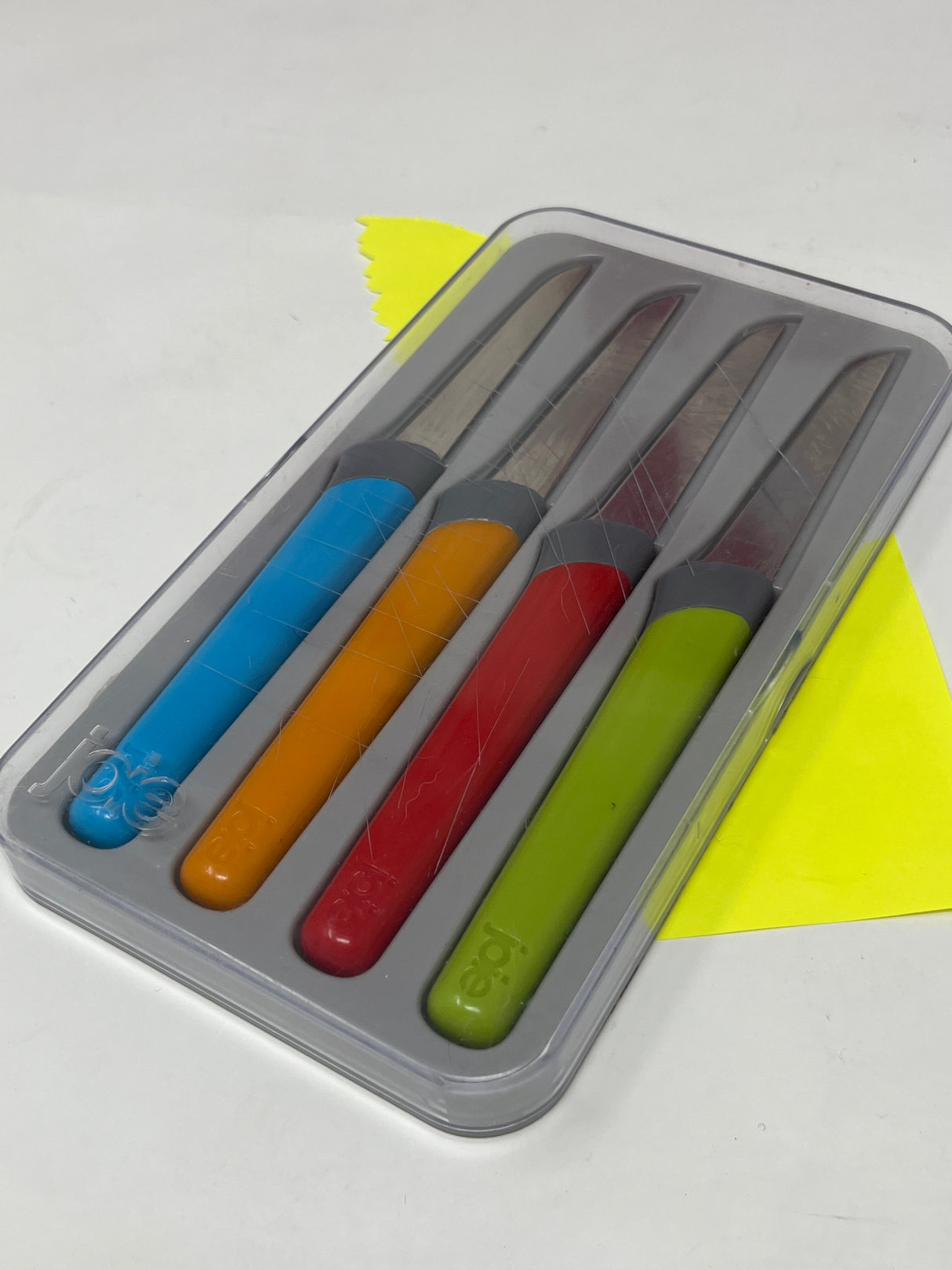 Joie set of 4 garnishing knives with colorful handles in a protective plastic container, ideal for intricate garnishing tasks.