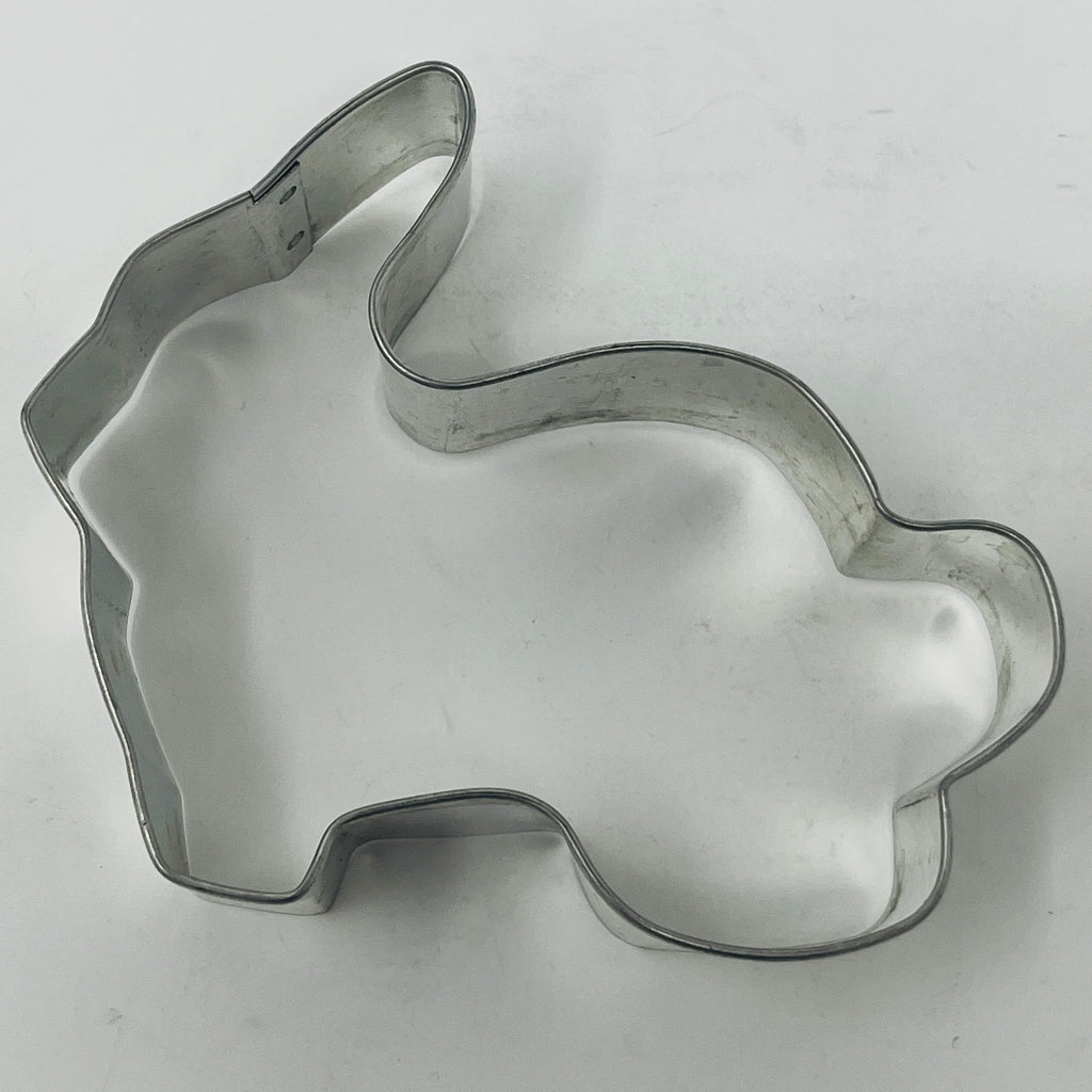 Mid century metal cookie cutter in rabbit shape on white surface.