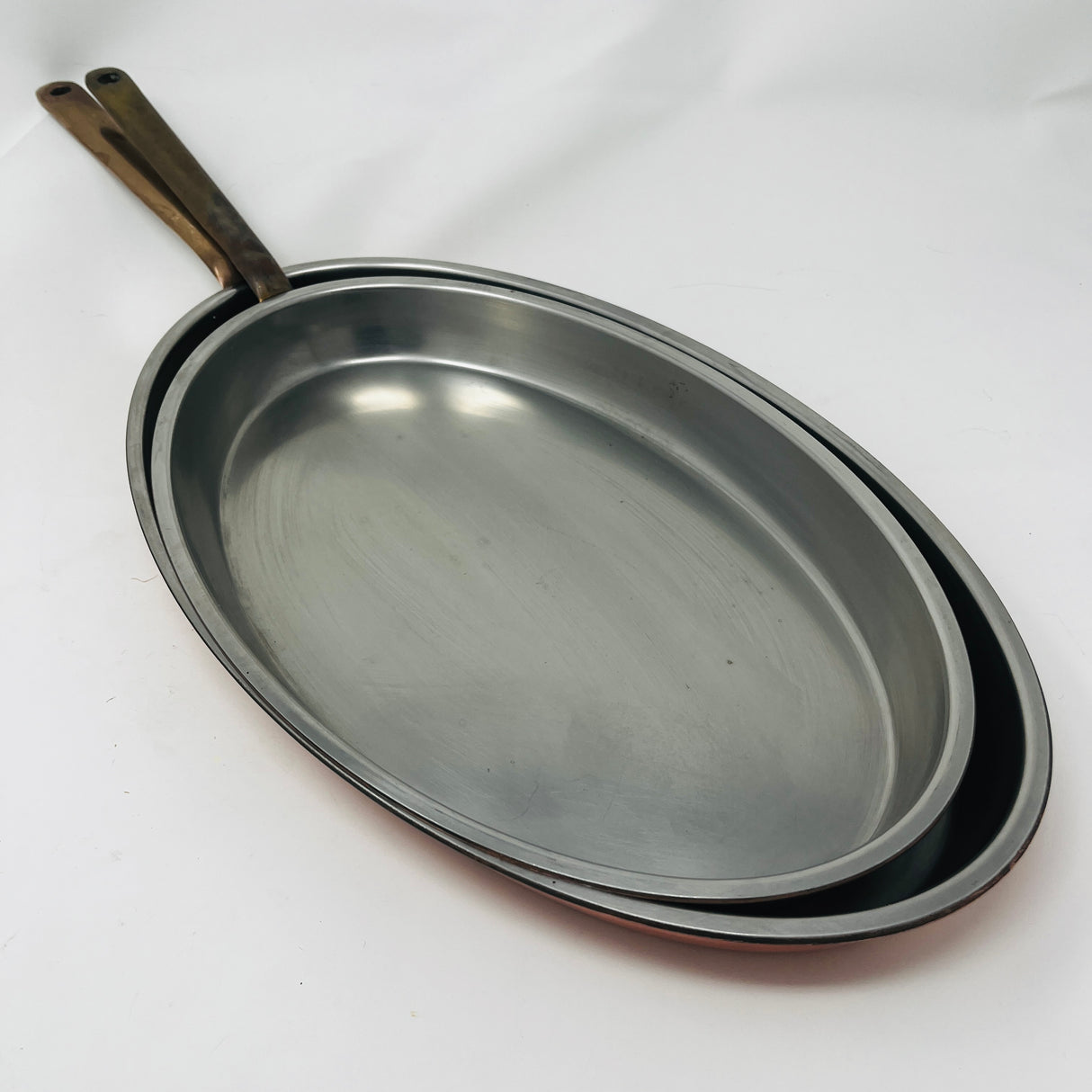 A pair of oval copper sauté pans with brass handles by Spring Culinox Switzerland. From Spoons Kitchen Exchange.