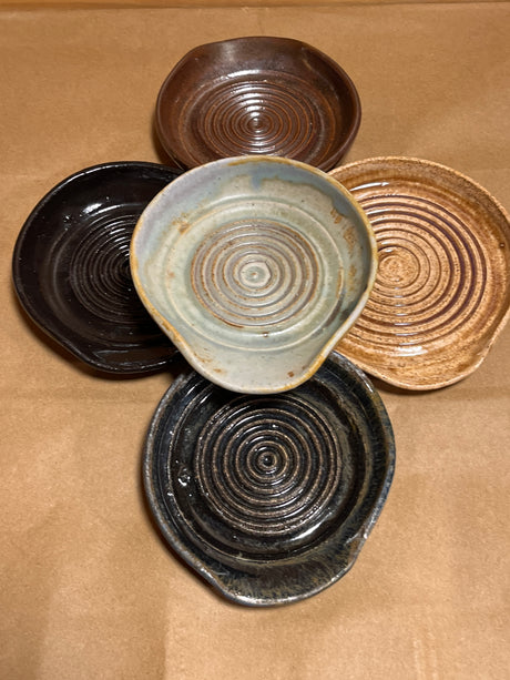Handmade ceramic garlic grater spoon rests by Charles Lehman, featuring five hand-thrown dishes with pinched lips and circular ridges, showcasing varied glaze finishes.