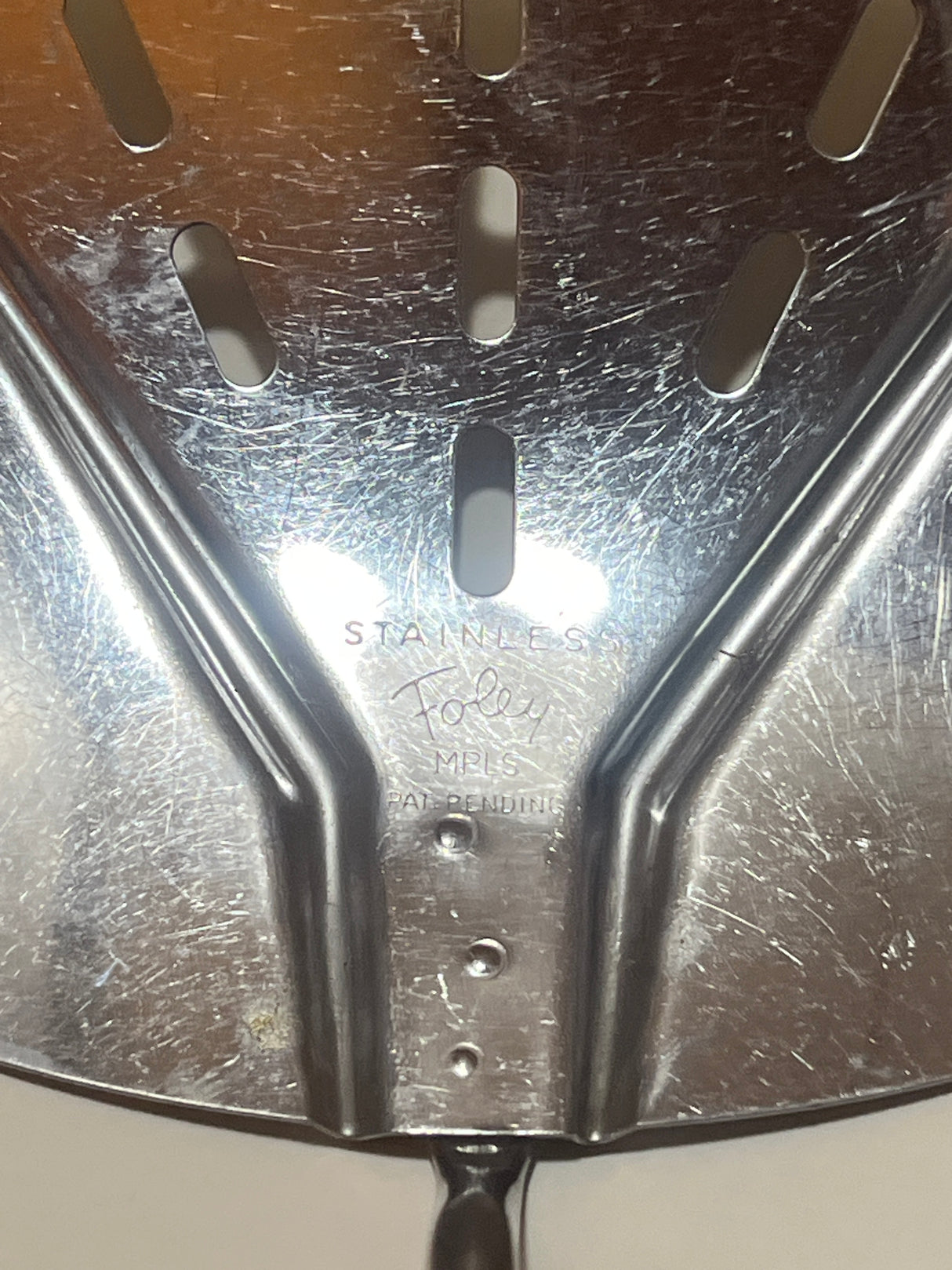Close-up of Foley Stainless Steel Wide Slotted Turner Lifter MPLS Curved Spatula head, showing reinforcing ribs and “STAINLESS · Foley · MPLS · PAT. PENDING” stamp.
