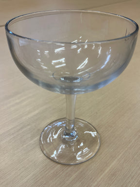 Large margarita/coupe glass on a table, containing liquid, highlighting its sleek design and transparent material, perfect for elegant drink presentation.