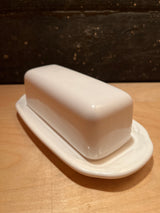 Covered white ceramic butter dish - Pfaltzgraff, featuring a classic two-piece design with a rectangular base and matching lid, displayed on a wooden surface.