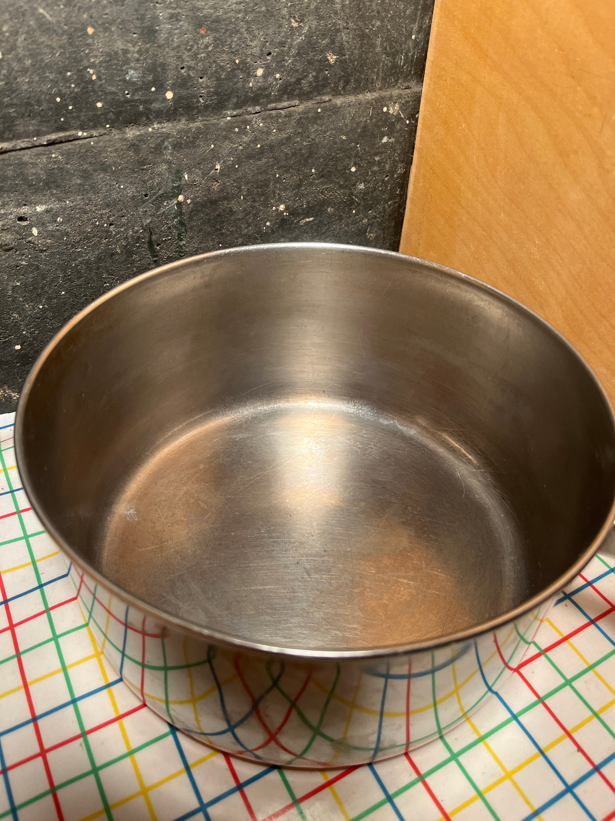 2-qt saucepan with copper bottom - vintage Revere Ware stainless steel, showcased empty on a tabletop. Features copper bottom and Bakelite handle with hanging ring.