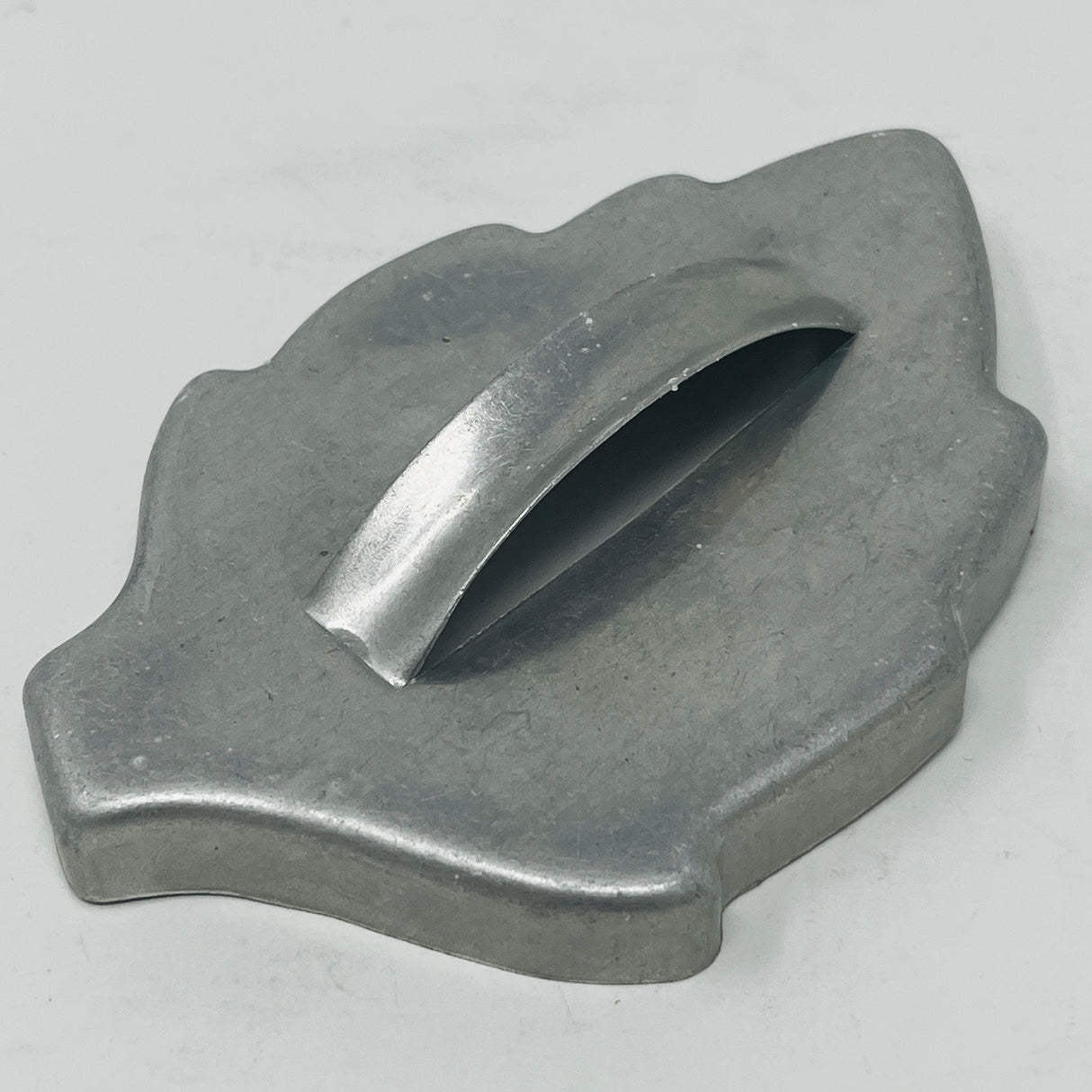 Mid century metal cookie cutter of a leaf with a large handle, close-up view. From Spoons Kitchen Exchange. 