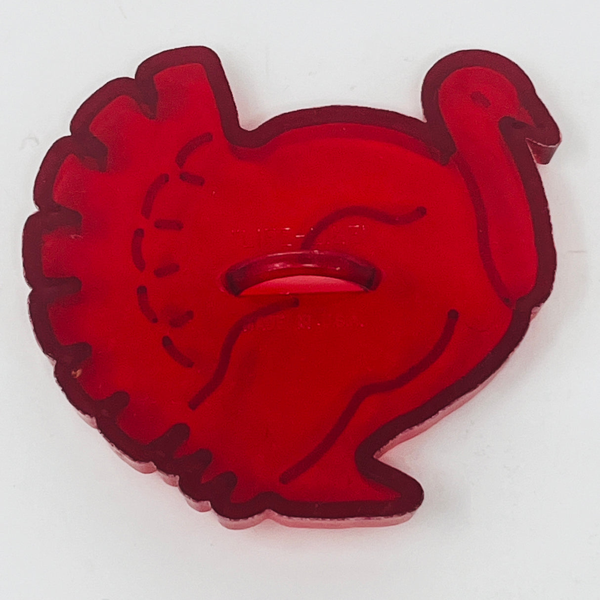 Vintage red plastic mid-century turkey shaped cookie cutter with ring detail.