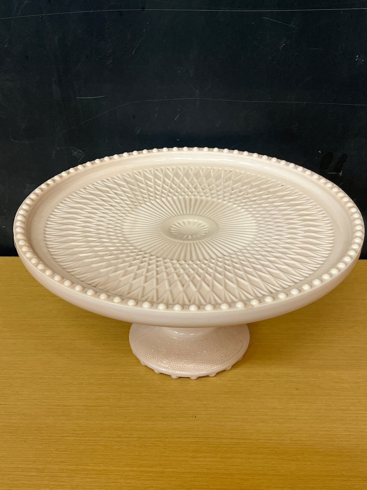 Jeanette pale pink milk glass pedestal candy dish with a geometric crisscross pattern and raised bumps, showcasing its vintage elegance from the 1950s-early 1960s.
