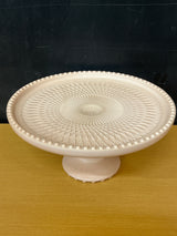 Jeanette pale pink milk glass pedestal candy dish with a geometric crisscross pattern and raised bumps, showcasing its vintage elegance from the 1950s-early 1960s.