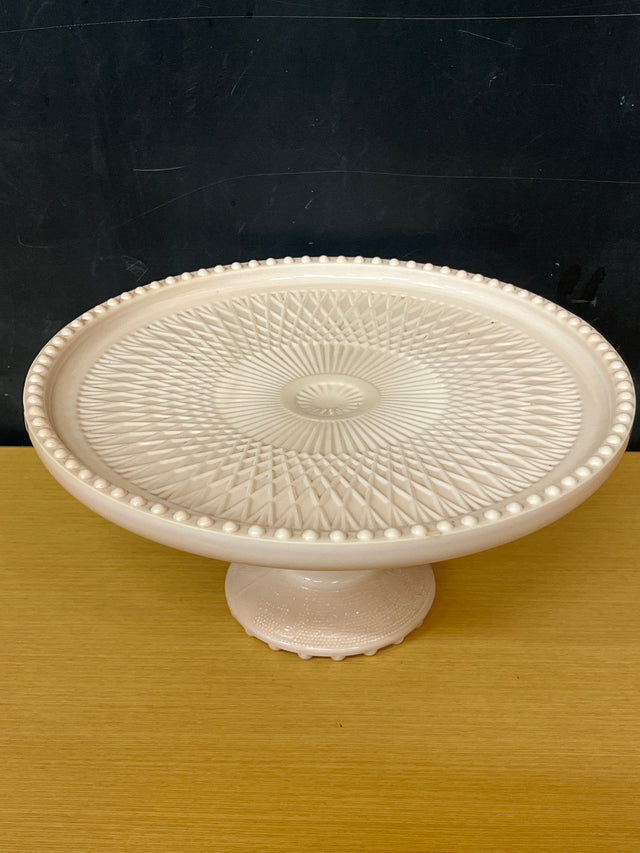 Jeanette pale pink milk glass pedestal candy dish with a geometric crisscross pattern and raised bumps, showcasing its vintage elegance from the 1950s-early 1960s.
