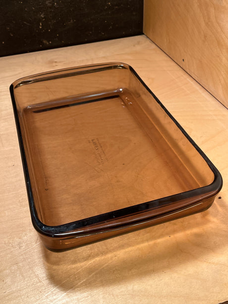 PYREX Corning Vision Ware amber baking dish, rectangular and glass, on wooden surface; vintage, durable borosilicate, minor scratches, excellent condition.