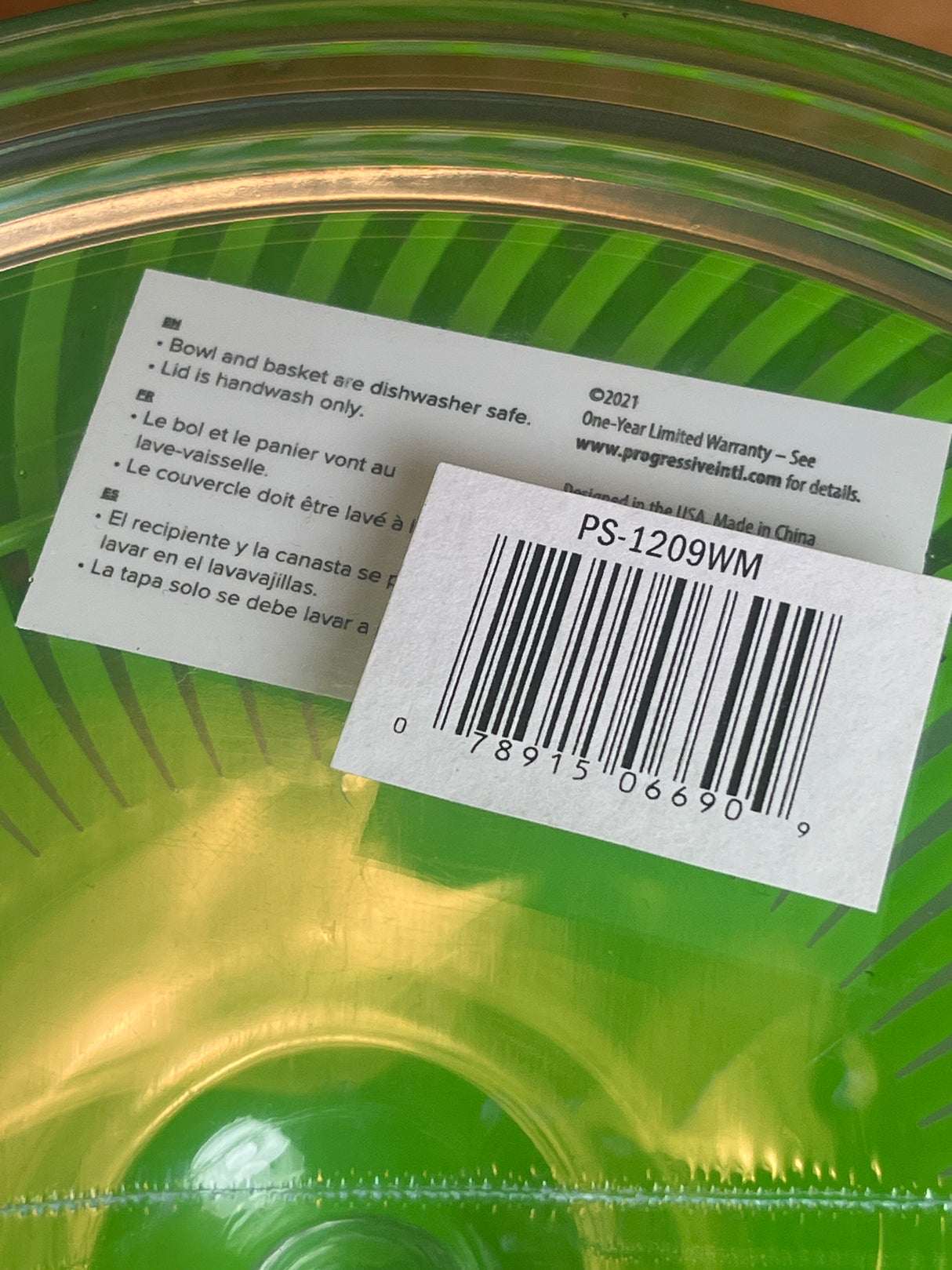 Easy Pull Salad Spinner by Prep Solutions, featuring a translucent green bowl with basket insert, shrink-wrapped, includes care instructions and price tag barcode, ideal for quick salad preparation.