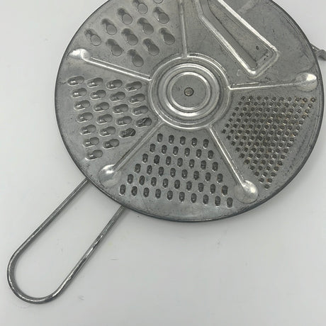 Vintage Foley Five-Setting Grater and Slicer, 1950s kitchenware. Circular metal object with holes, close-up of metal surface. Good condition with sharp slicer blade, gentle cleaning due to rust.