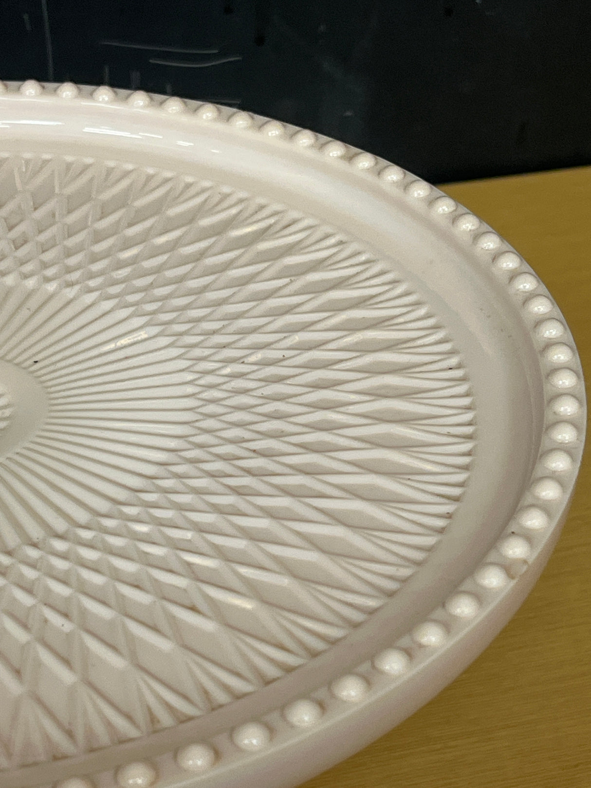 Jeanette pale pink milk glass pedestal candy dish with geometric crisscross pattern and raised bumps on the rim, showcasing a vintage 1950s-60s design.