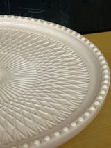 Jeanette pale pink milk glass pedestal candy dish with geometric crisscross pattern and raised bumps on the rim, showcasing a vintage 1950s-60s design.